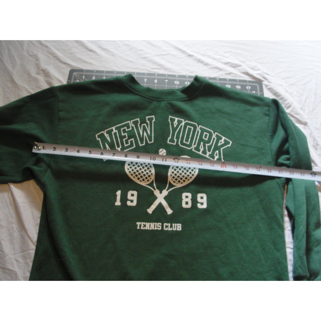 Green crewneck sweatshirt featuring a "New York 1989 Tennis Club" graphic.